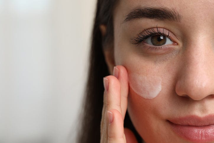 woman with dry skin mousturising face